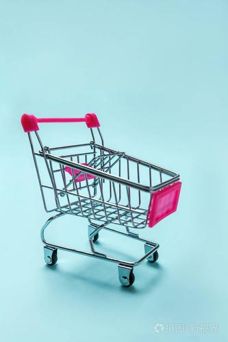 小超市杂货店推车为购物玩具与车轮隔离在蓝色粉彩纸时尚背景.